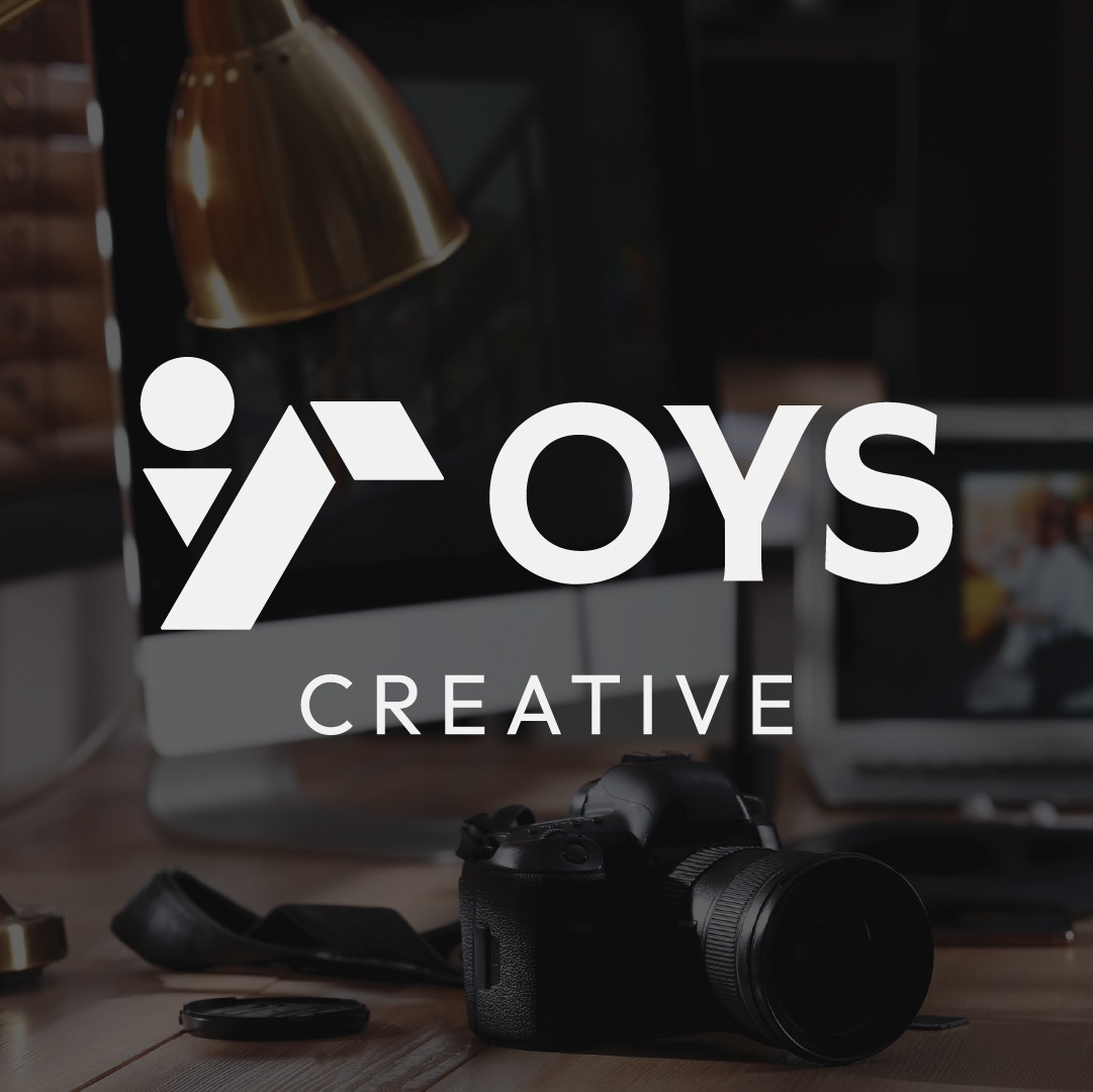 OYS Creative studio workstation mockup featuring creative camera gear, desktop display, and illuminated white brandmark